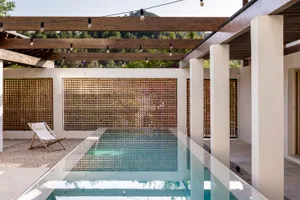 A sleek, modern minimalist swimming pool deck with glass walls and a concrete patio area, designed for a contemporary aesthet
