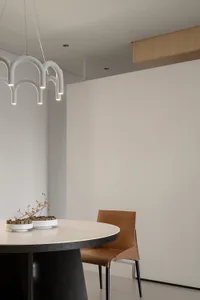 A modern minimalist dining room featuring concrete furniture and a minimalist light fixture.