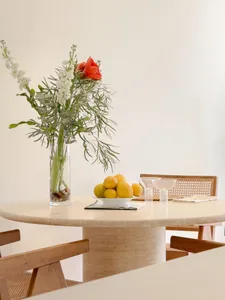 A minimalist dining room with a stone table, a vase of flowers, and lemons on a plate.