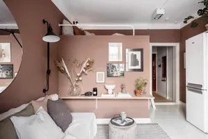 A minimalist living room with white wood finishes, featuring a white sofa adorned with white and gray pillows, a coffee table