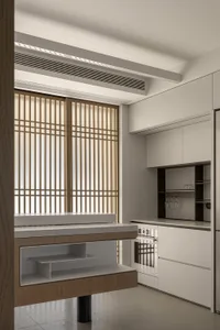 A minimalist residential kitchen featuring white cabinets and wood accents, with a modern design and a clean, organized layou