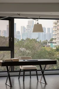 A modern home office desk situated in front of a large window overlooking a cityscape.