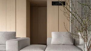 A modern living room with wooden panel walls and gray upholstered furniture.