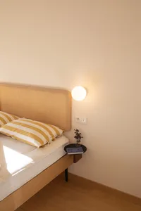 A minimalist bedroom with a wooden bed and yellow-striped pillows.