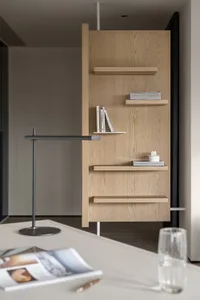 A modern office space featuring wooden shelves with books and a lamp.
