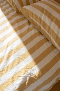A cozy bedroom scene featuring modern striped yellow and white pillows on a bed.