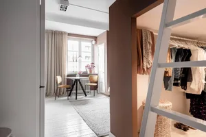 A minimalist white home office with white wooden floors, a white table, and white chairs.