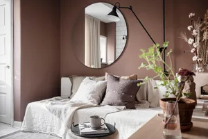 A cozy living room with textured fabric furnishings and a round mirror