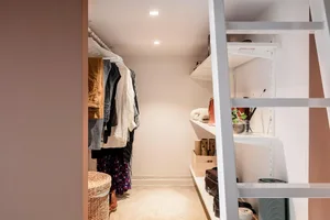 A minimalist closet with white metal shelving for clothing storage.