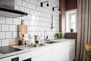 A modern kitchen with white subway tiles, white countertop, and stainless steel appliances.