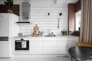A minimalist modern white kitchen with white subway tiles and stainless steel appliances.