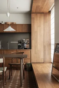 A modern kitchen with minimalist design featuring wooden cabinets and floor.
