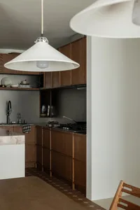 Modern minimalist kitchen featuring natural wood cabinets and marble countertops.
