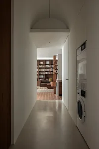 A modern contemporary living room with concrete flooring and a large bookshelf filled with books.