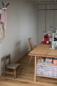 A wooden table with a sewing machine and various materials in a home office/craft room setting.