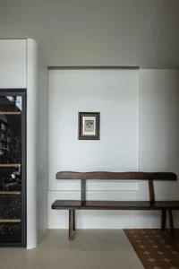 Modern minimalist interior with wooden bench and glass cabinet.