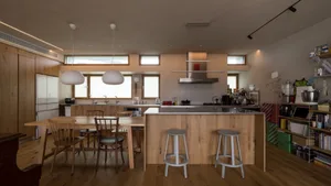 Modern kitchen featuring a wooden island and stools, with a pendant light hanging above the dining table and a stainless stee