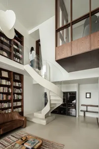 A modern interior design featuring a concrete staircase with glass railings in a library setting.