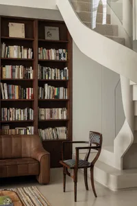 A modern library featuring wooden bookshelves filled with books and a comfortable leather sofa.