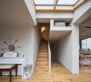 Modern minimalist staircase and loft space with wooden stairs, cement floors, and exposed beams.