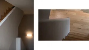 A minimalist staircase made of wood, with a warm light fixture mounted on the wall.