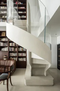 A modern white staircase with a glass railing in a library setting.