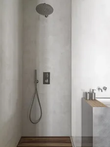 A minimalist bathroom with concrete walls and a wooden floor.