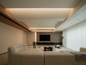 A modern, geometric living room with a hyphenated design aesthetic, featuring a fabric sofa, concrete flooring, and marble ac