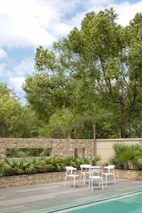 A serene outdoor relaxation space featuring modern furniture, stone and concrete elements, surrounded by lush greenery.