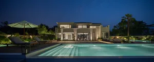 A modern residential exterior illuminated with concrete and glass features.