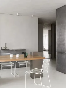 Modern minimalist kitchen with metallic countertop and white cabinets.
