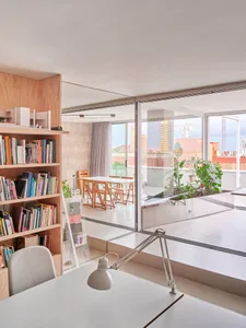 Minimalist living room with concrete walls, a white desk, and a bookshelf