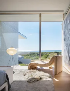 Modern minimalist residential interior featuring large glass window overlooking natural landscape.