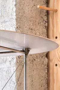 A modern interior design featuring an airfoil-shaped metal structure against a concrete wall.