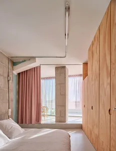 A modern bedroom featuring concrete and wooden elements.