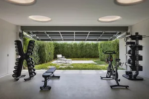 A modern home gym with concrete flooring, dumbbells, and an exercise bike.