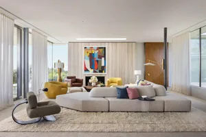 A modern living room featuring a fabric sofa, yellow armchairs, and a geometric abstract painting.