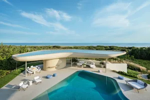 Modern, minimalist pool house featuring a concrete structure and a serene ocean view.