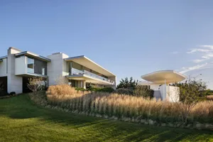 Modern residential exterior featuring large glass windows and a sleek design.