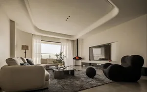 Contemporary living room featuring neutral-toned fabrics and tiles, a black rocking chair, and a suspended fireplace.