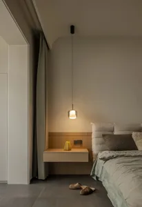 Minimalist bedroom with a wooden floating nightstand and a yellow lantern.