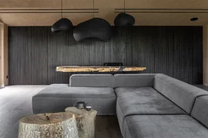 Industrial-style living room featuring wooden slat walls, a sectional sofa, and a rustic wooden coffee table with a tea set.