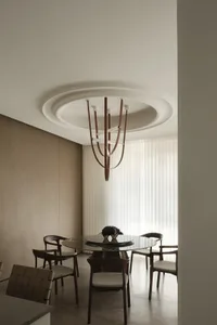 A minimalist dining room with a round glass table, wooden chairs, and a modern chandelier.