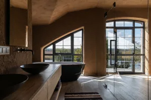 A modern bathroom featuring two black bathtubs, wooden flooring, and concrete walls.