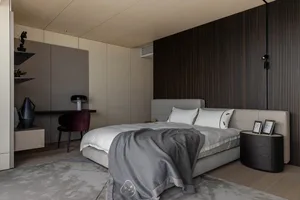 Modern bedroom featuring grey flooring with a textured wood pattern, a grey upholstered bed with white bedding, and a minimal