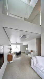 A modern living room with a minimalist design, featuring concrete walls and furniture.