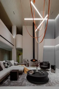 A modern interior living room with a concrete fireplace, wooden furniture, and glass elements.