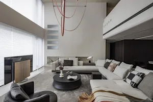 A modern living room with a white sectional sofa, round black coffee table, and large windows.