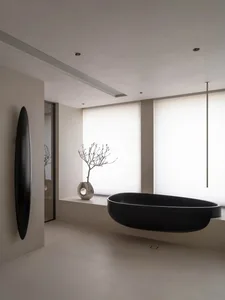 Modern minimalist bathroom featuring a black concrete bathtub with a minimalist vase on a windowsill and a minimalist vase.