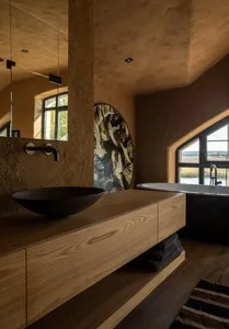 Modern minimalist bathroom featuring a wood vanity with a black bowl sink and a ceramic bathtub.